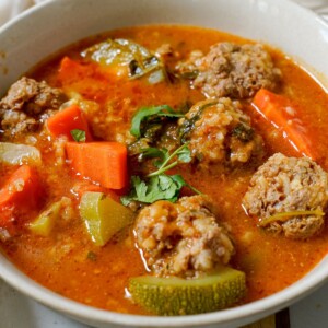 a close-up of albondigas soup in a white bowl