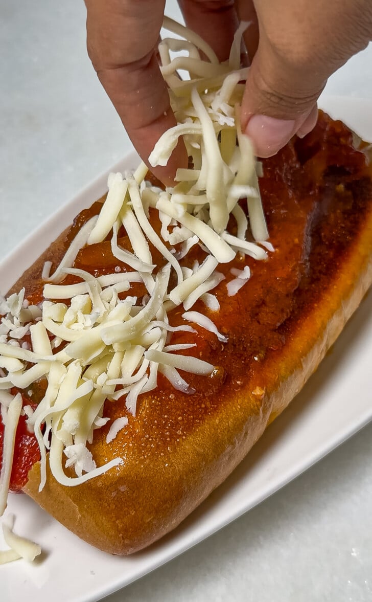 adding cheese to an Italian sausage sandwich