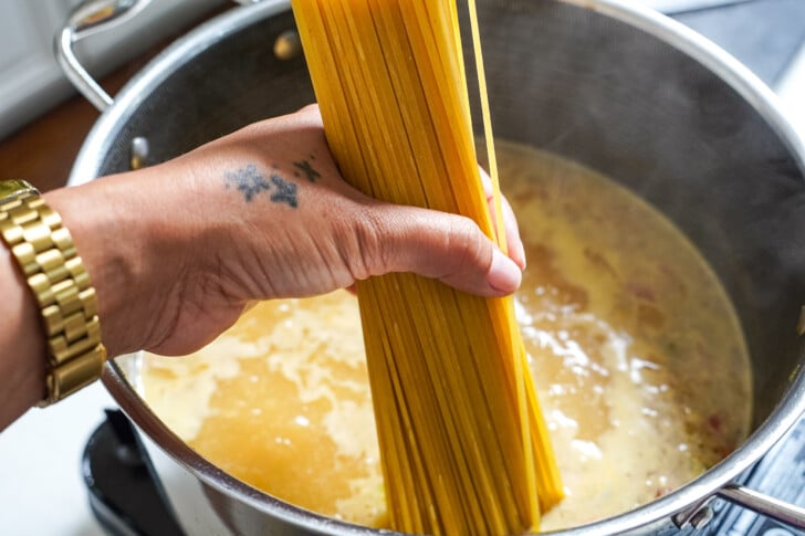 placing a handful of pasta into a large pot of liquid