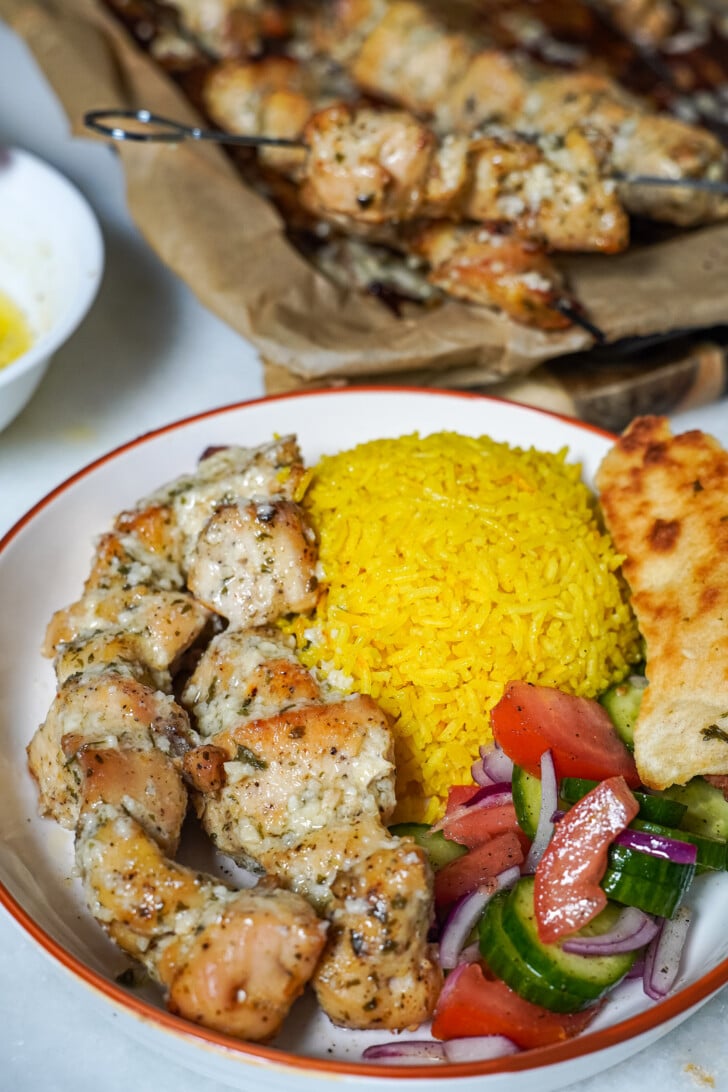 chicken and rice in a white bowl with a salad