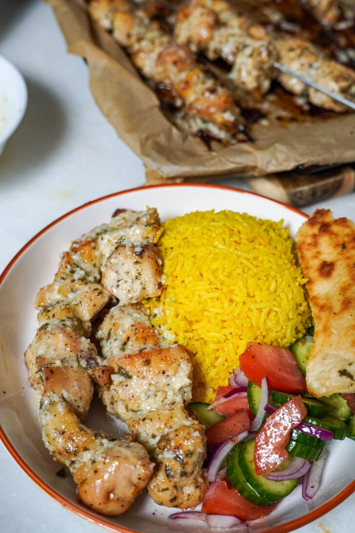 chicken skewers in a bowl with rice and a small salad