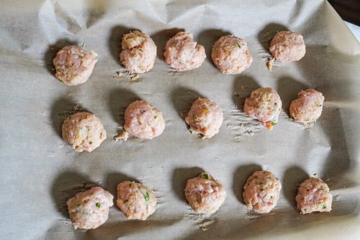 chicken meatballs rolled out and placed on a sheet pan