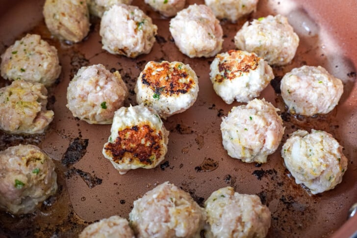 chicken meatballs searing in a skillet