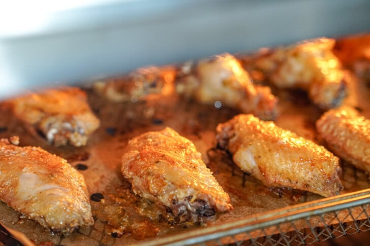 chicken wings cooking in an air fryer on a tray