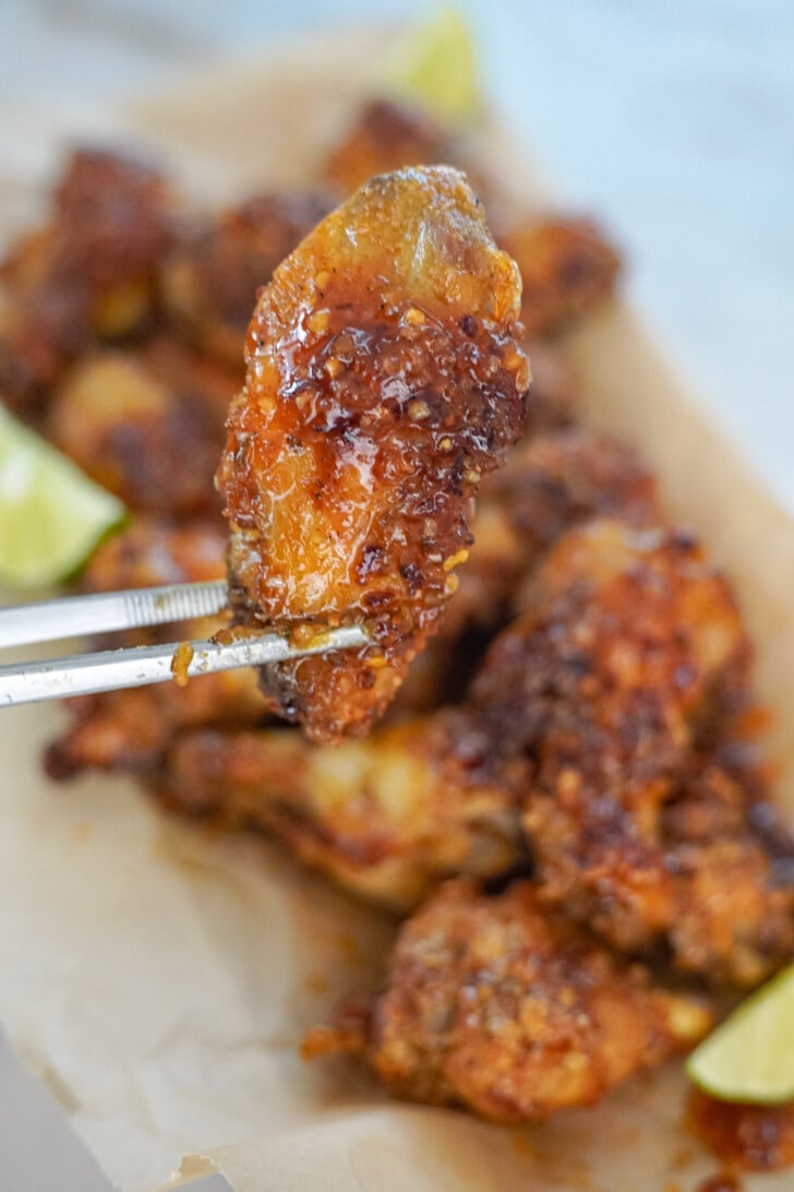 holding a chili lime chicken wing with tongs