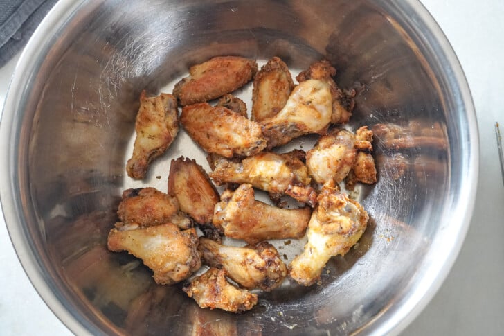 chicken wings in a bowl to have chili lime sauce poured on them