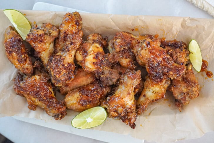 a platter of chicken wings with lime wedges on the side