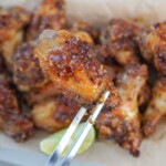 holding a chili lime chicken wing with tongs