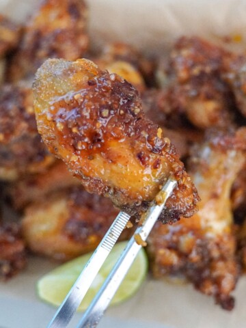 holding a chili lime chicken wing with tongs